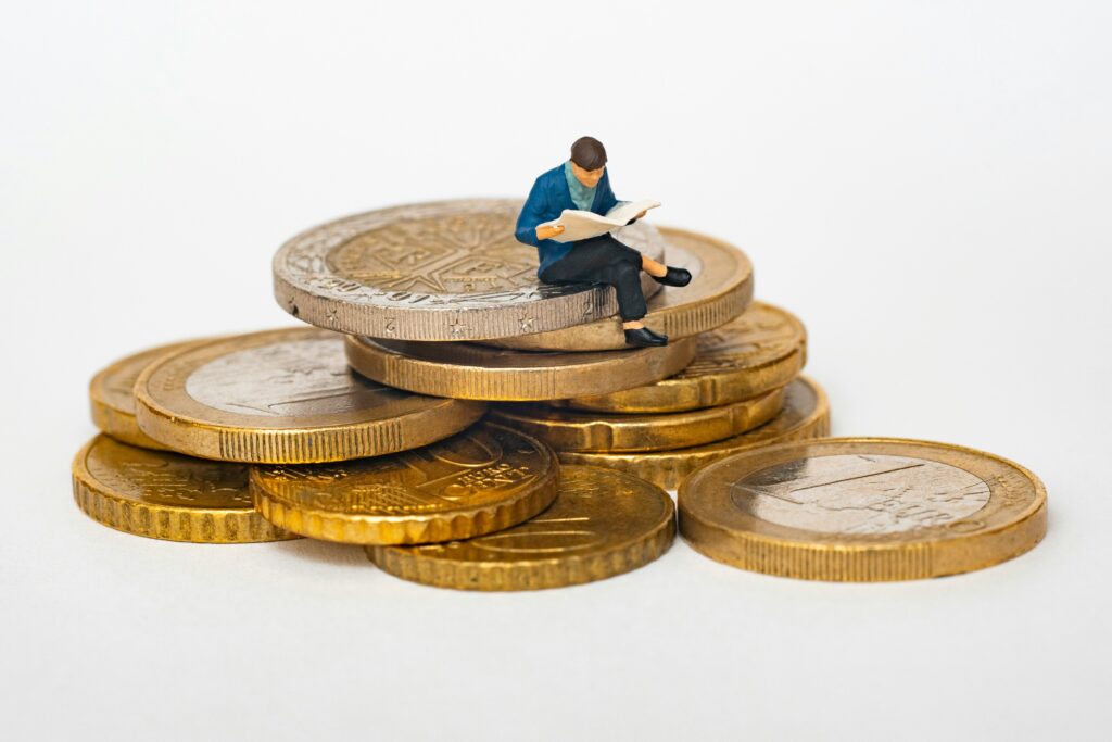 Miniature businessman sitting on top of a pile of coins, symbolizing MCA business loans and startup capital growth